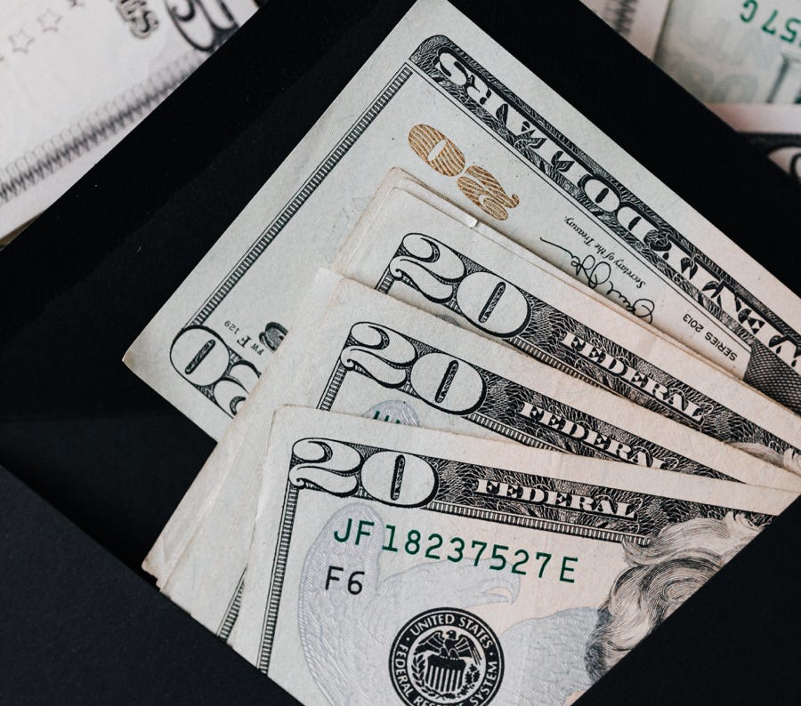 Stack of dollars and black envelope with banknotes inside
