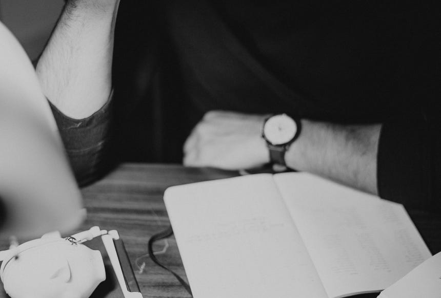 Crop pondering man analyzing expenses and taking notes